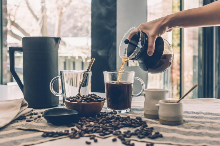 Inviting scene of fresh coffee being poured with scattered coffee beans on a wooden table.
